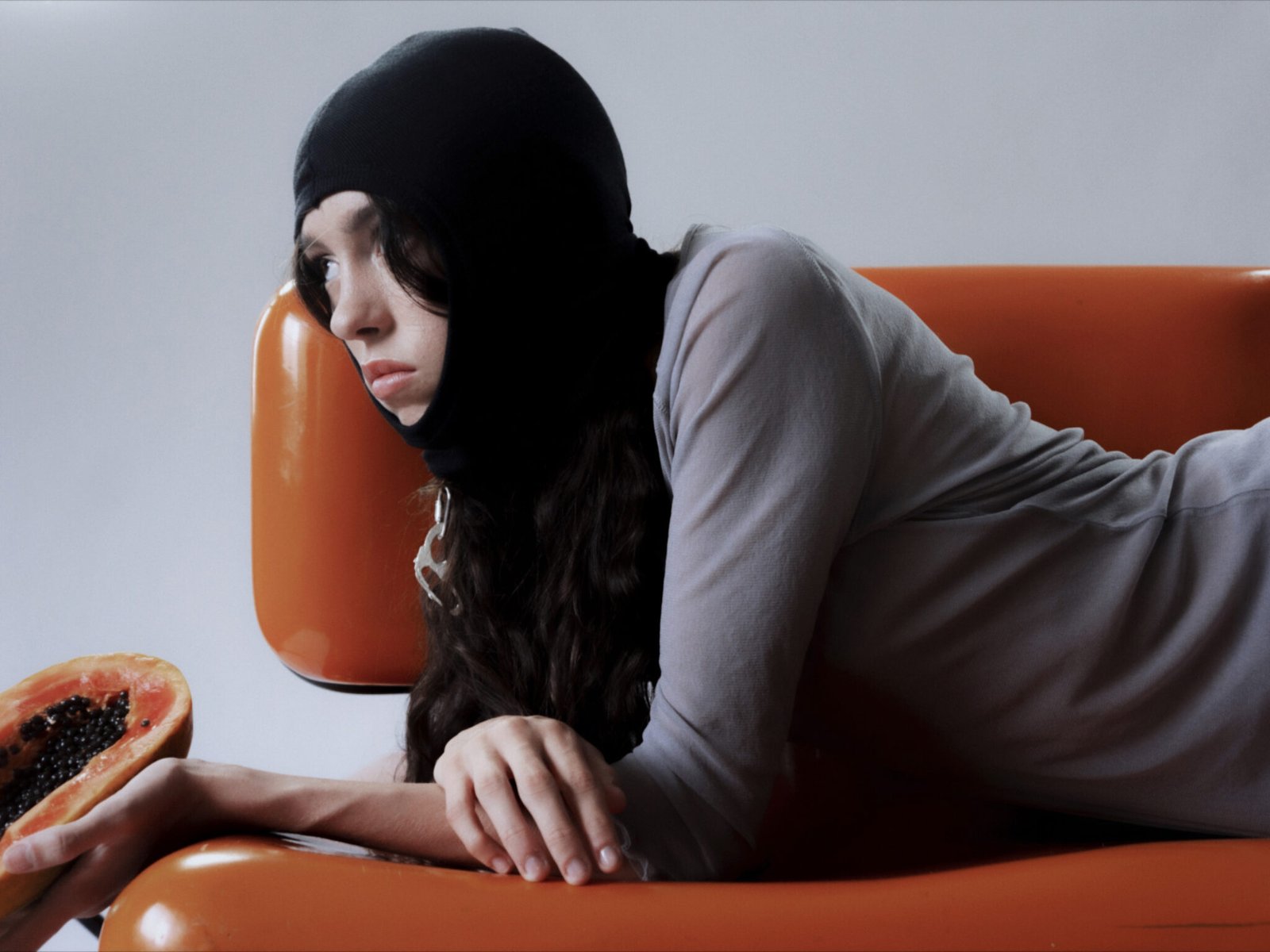 foto creativa de una mujer en un sofa naranja sujetando fruta